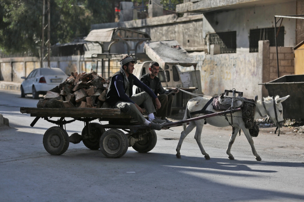 A Syrian man transports wood in a donkey cart in Douma, a rebel-held town on the outskirts of the capital Damascus, on October 24, 2017. 

 According to the World Bank, the conflict in Syria has cost the country's economy some $226 billion -- about four times the country's gross domestic product in 2010. The fighting has damaged or destroyed 27 percent of Syria's housing stock and about half the country's medical and educational facilities. About 85 percent of the population lives below the poverty line and half are unemployed. 
 / AFP / Amer ALMOHIBANY
