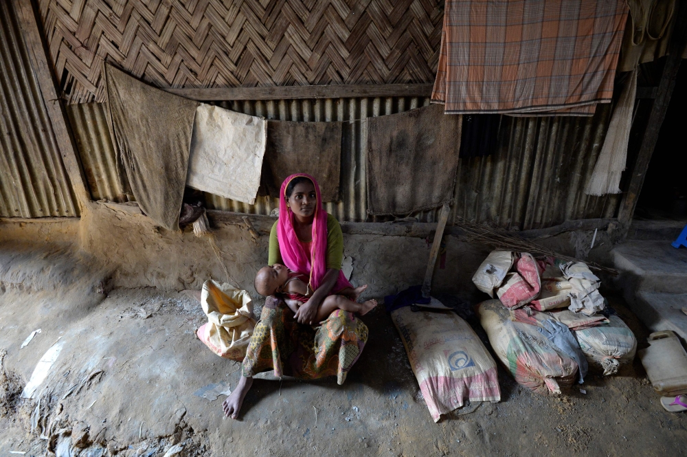 A Rohingya Muslim refugee holds a child at a makeshift shelter at Kutupalong refugee camp in the Bangladeshi district of Ukhia on October 25, 2017. Myanmar and Bangladesh have agreed to work together to repatriate hundreds of thousands of Rohingya Muslim refugees, officials said, but details remain thin as the humanitarian crisis deepens. Ties between the neighbours have been severely strained by army-led violence in Myanmar's Rakhine state that has driven more than 600,000 Rohingya into Bangladesh since late August. / AFP / TAUSEEF MUSTAFA
