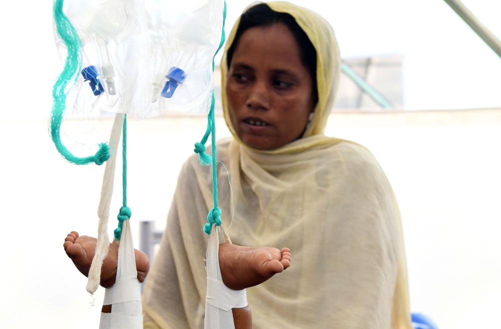 Rohingya Muslim refugee Shakira Bejum sits with her grandchild Shaid-Ullah at a Red Cross clinic near Kutupalong refugee camp in the Bangladeshi district of Ukhia on October 25, 2017. Myanmar and Bangladesh have agreed to work together to repatriate hundreds of thousands of Rohingya Muslim refugees, officials said, but details remain thin as the humanitarian crisis deepens. Ties between the neighbours have been severely strained by army-led violence in Myanmar's Rakhine state that has driven more than 600,000 Rohingya into Bangladesh since late August. / AFP / TAUSEEF MUSTAFA
