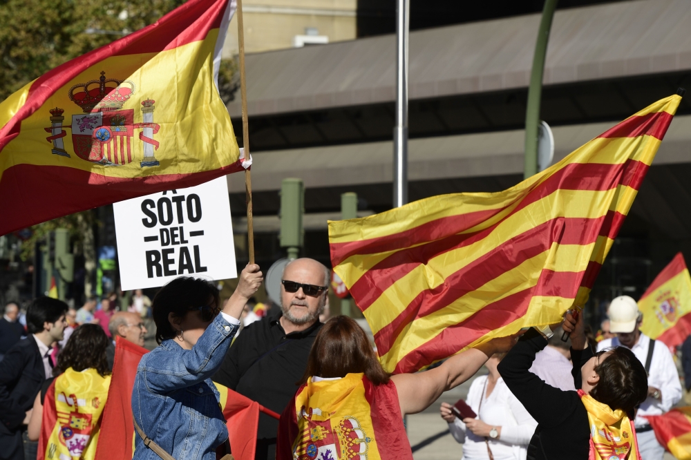 People wave Spanish flags along with Catalonia's Senyera flag (R) during a demonstration calling for unity in Madrid on October 28, 2017, a day after direct control was imposed on Catalonia over a bid to break away from Spain. Spain moved to assert direct rule over Catalonia, replacing its executive and top functionaries to quash an independence drive that has plunged the country into crisis and unnerved secession-wary Europe. / AFP / JAVIER SORIANO
