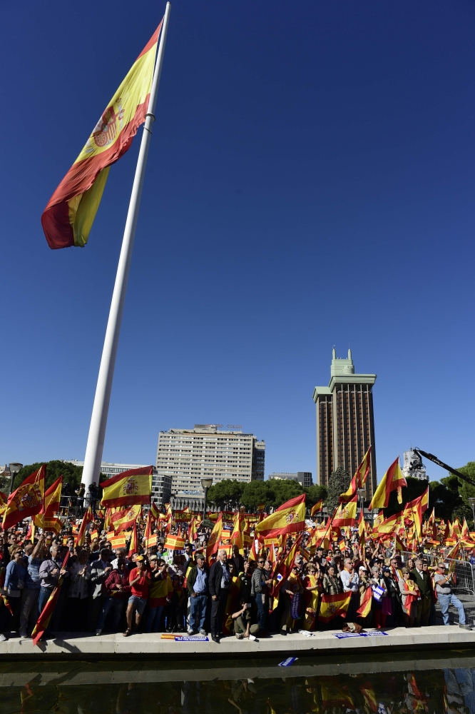 A giant Spanish flag flutters as people wave Spanish flags during a demonstration calling for unity at Plaza de Colon in Madrid on October 28, 2017, a day after direct control was imposed on Catalonia over a bid to break away from Spain. Spain moved to assert direct rule over Catalonia, replacing its executive and top functionaries to quash an independence drive that has plunged the country into crisis and unnerved secession-wary Europe. / AFP / JAVIER SORIANO
