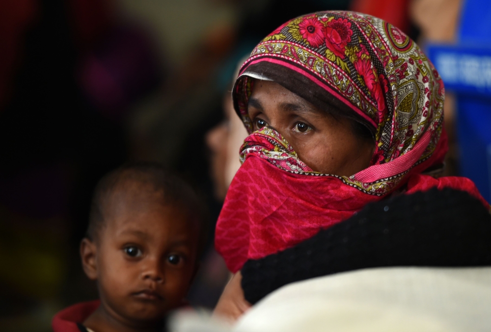 In this photograph taken on October 24, 2017, Rohingya Muslim refugees wait inside a government-run family planning centre in the Bangladeshi town of Palongkhali. Bangladesh is planning to introduce voluntary sterilisation in its overcrowded Rohingya camps, where nearly a million refugees are fighting for space, after efforts to encourage birth control failed.
 / AFP / Tauseef MUSTAFA
