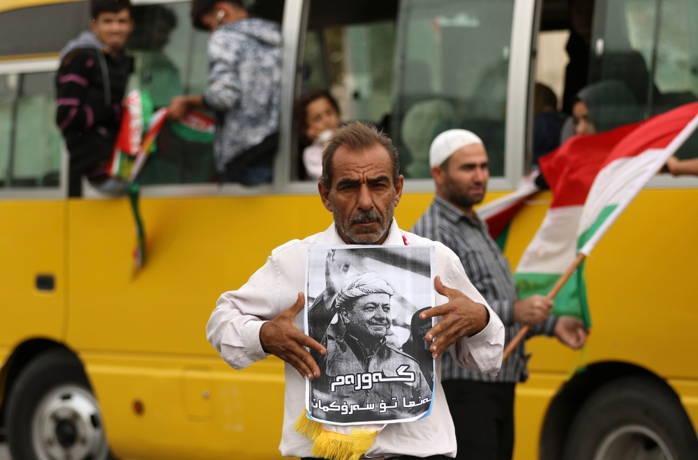 An Iraqi Kurd holds a poster portraying the Iraqi Kurdish leader Massud Barzani, during a protest in support of him, in Arbil, the capital of autonomous Iraqi Kurdistan, on October 30, 2017. Long-time Kurdish leader Massud Barzani, the architect of the referendum, announced on October 29, 2017 he is stepping down after it led to Iraq's recapture of almost all disputed territories that had been under Kurdish control. / AFP / SAFIN HAMED 