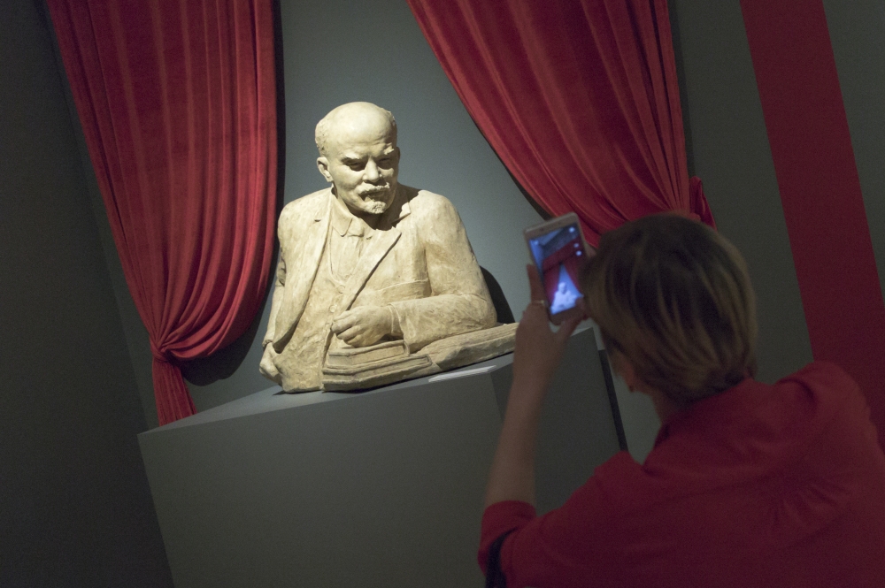 A woman photographs the sculpture of Soviet founder Vladimir Lenin during the opening of 