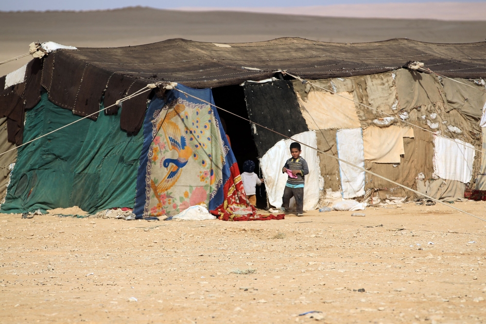 Iraqi children, displaced from the city of al-Qaim, stand outside a tent near al-Qaim, in western Anbar province, on the Syrian border on November 2, 2017. / AFP / AHMAD AL-RUBAYE
