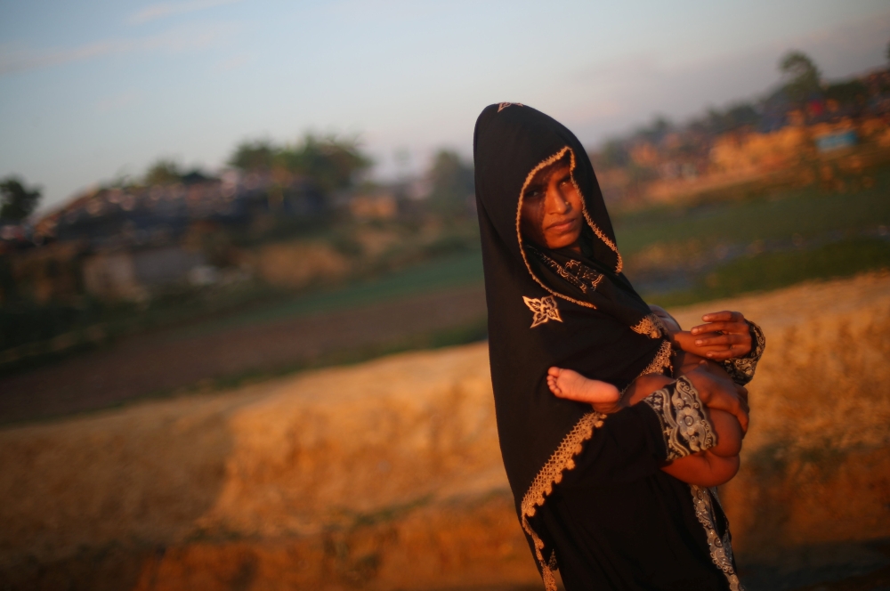 A Rohingya refugee carries her child through the Kutupalong refugee camp at sunset near Cox's Bazar, Bangladesh, November 4, 2017. REUTERS/Hannah McKay