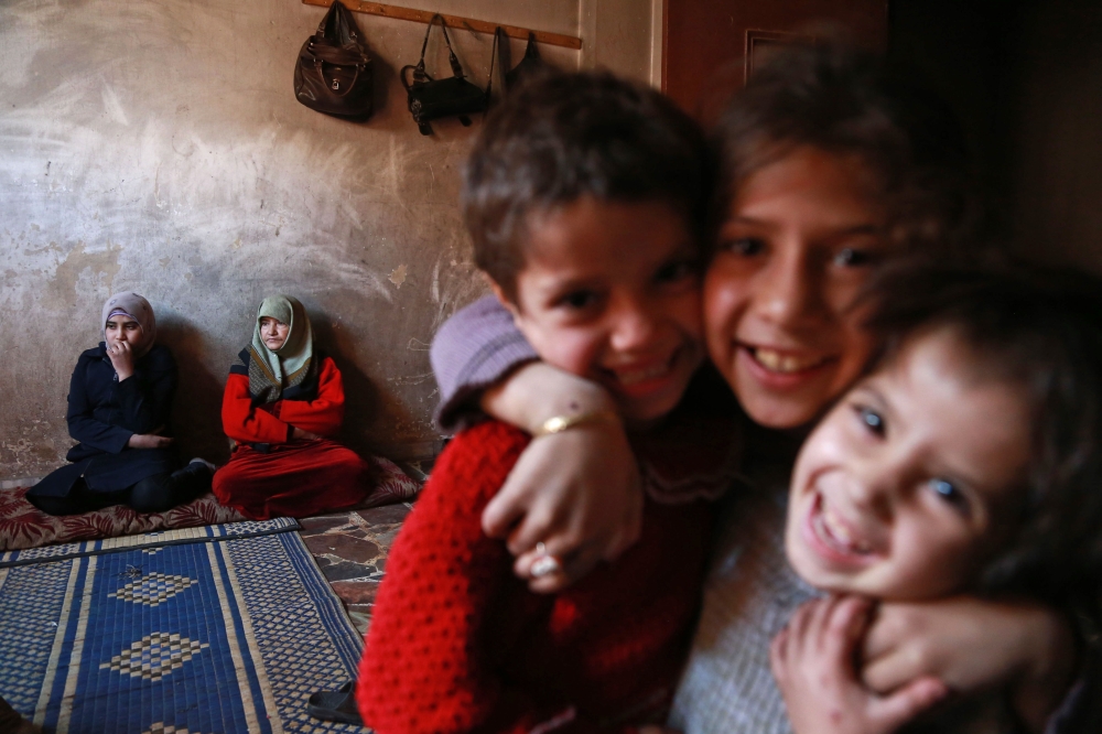 Children pose for a photo as members of the family of Umm Saeed gather in their house on November 6, 2017 in Saqba, in the besieged rebel-held Eastern Ghouta area near Damascus, where residents and relief groups have warned a humanitarian crisis is escalating. Eastern Ghouta was once a prime agricultural region famed for its orchards, but the rebel stronghold has been under a tight government siege since 2013, causing shortages of food and medicine.
 / AFP / ABDULMONAM EASSA
