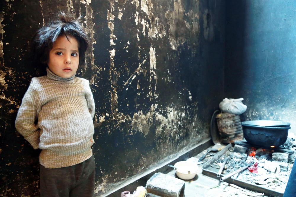 Three-year-old Yasmine from the family of Umm Saeed waits to be served a meal of corn and cabbage on November 6, 2017 in Saqba, in the besieged rebel-held Eastern Ghouta area near Damascus, where residents and relief groups have warned a humanitarian crisis is escalating. Eastern Ghouta was once a prime agricultural region famed for its orchards, but the rebel stronghold has been under a tight government siege since 2013, causing shortages of food and medicine.
 / AFP / ABDULMONAM EASSA
