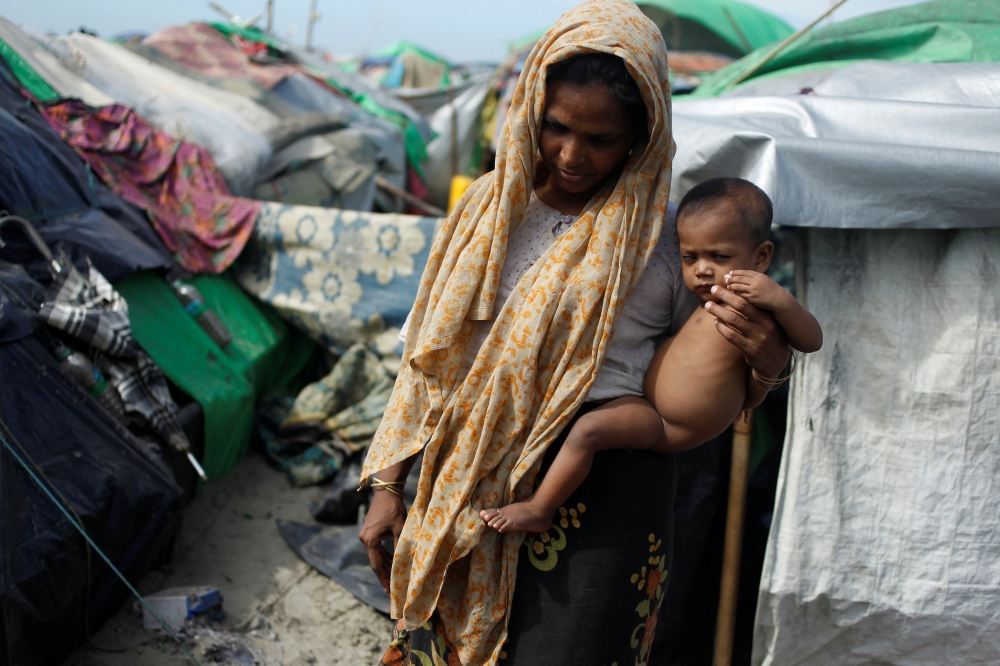 A Rohingya Muslim woman holds a baby as they wait to cross the border to go to Bangladesh, in a temporary camp outside Maungdaw, northern Rakhine state, Myanmar November 12, 2017. REUTERS/Wa Lone