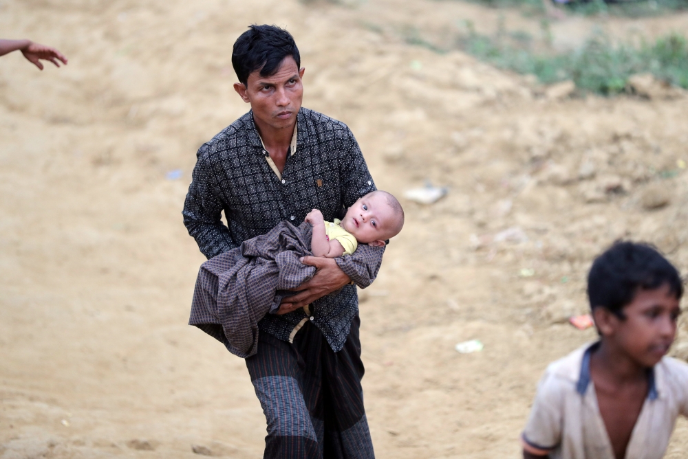 A Rohingya refugee man carries a child in the Palong Khali refugee camp in Cox's Bazar, Bangladesh, November 17, 2017. REUTERS/Mohammad Ponir Hossain