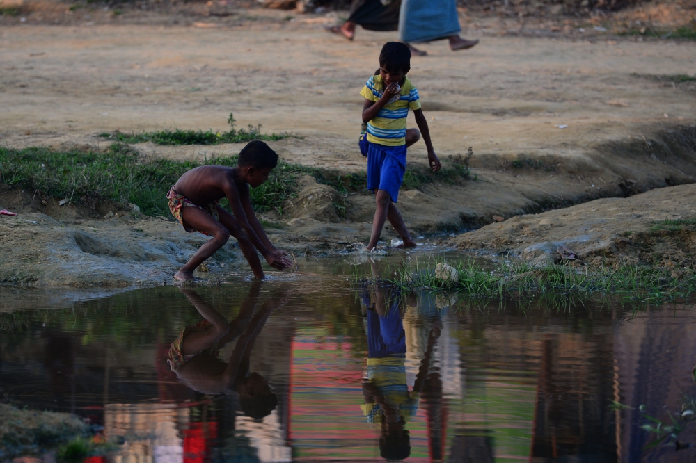 Rohingya Muslim refugees catch fish in Thankhali refugee camp in the Bangladeshi district of Ukhia on November 25, 2017. An estimated 618,000 Muslim Rohingya have fled mainly Buddhist Myanmar since a military crackdown was launched in Rakhine in August triggered an exodus, straining resources in the impoverished country. / AFP / Munir UZ ZAMAN
