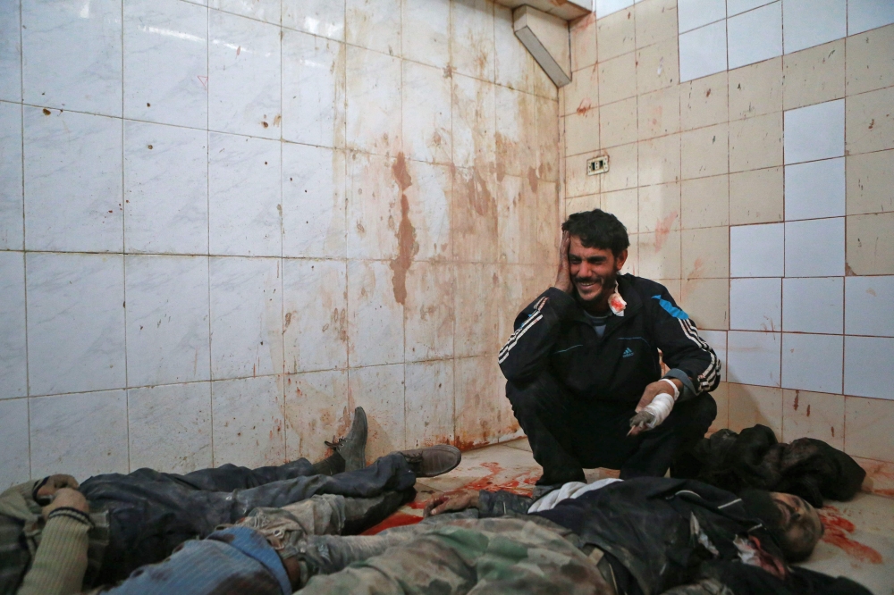 EDITORS NOTE: Graphic content / A Syrian man mourns over the body of a relative at a makeshift morgue in the rebel-controlled town of Hamouria, in the eastern Ghouta region on the outskirts of the capital Damascus, on November 27, 2017, following reported bombardment by government forces. / AFP / ABDULMONAM EASSA
