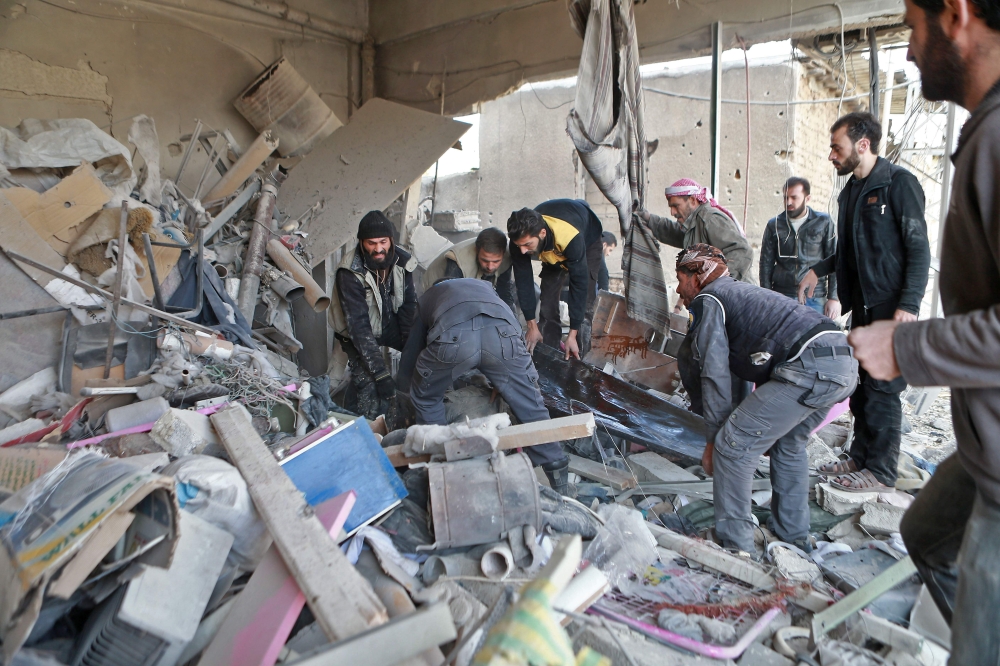 Members of the Syrian Civil Defence, known as the white helmets, carry a body out of the rubble in the rebel-controlled town of Mudayra, in the eastern Ghouta region on the outskirts of the capital Damascus, on November 27, 2017, following reported bombardment by government forces. 
 / AFP / ABDULMONAM EASSA
