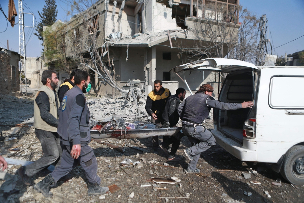 Members of the Syrian Civil Defence, known as the white helmets, carry a body out of the rubble in the rebel-controlled town of Mudayra, in the eastern Ghouta region on the outskirts of the capital Damascus, on November 27, 2017, following reported bombardment by government forces. 
 / AFP / ABDULMONAM EASSA
