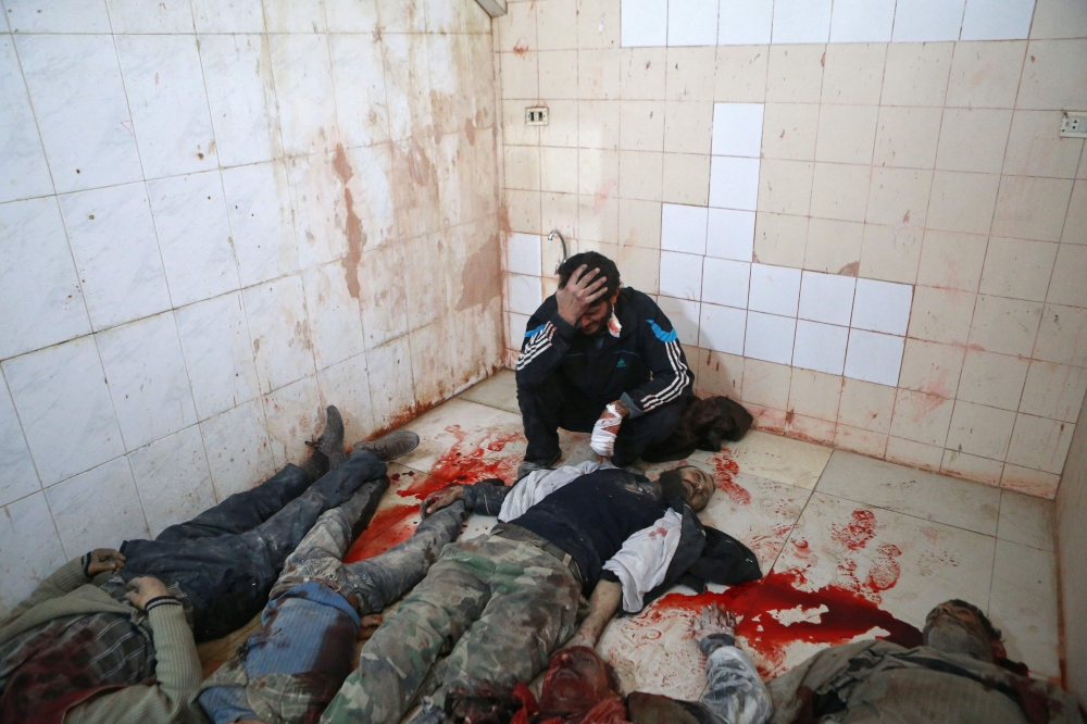 EDITORS NOTE: Graphic content / A Syrian man mourns over the body of a relative at a makeshift morgue in the rebel-controlled town of Hamouria, in the eastern Ghouta region on the outskirts of the capital Damascus, on November 27, 2017, following reported bombardment by government forces. / AFP / ABDULMONAM EASSA
