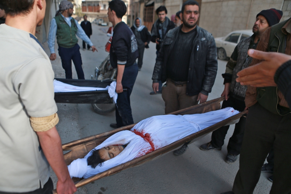 EDITORS NOTE: Graphic content / Syrian men carry the shrouded body of a boy at a makeshift morgue in the rebel-controlled town of Hamouria, in the eastern Ghouta region on the outskirts of the capital Damascus, on November 27, 2017, following reported bombardment by government forces. / AFP / ABDULMONAM EASSA
