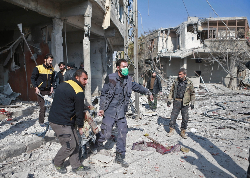 Members of the Syrian Civil Defence, known as the white helmets, carry a body out of the rubble in the rebel-controlled town of Mudayra, in the eastern Ghouta region on the outskirts of the capital Damascus, on November 27, 2017, following reported bombardment by government forces. 
 / AFP / ABDULMONAM EASSA
