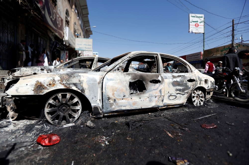 People go about their day near cars damaged during recent clashes between Houthi fighters and forces loyal to Yemen's former president Ali Abdullah Saleh in Sanaa, Yemen December 5, 2017. REUTERS/Khaled Abdullah