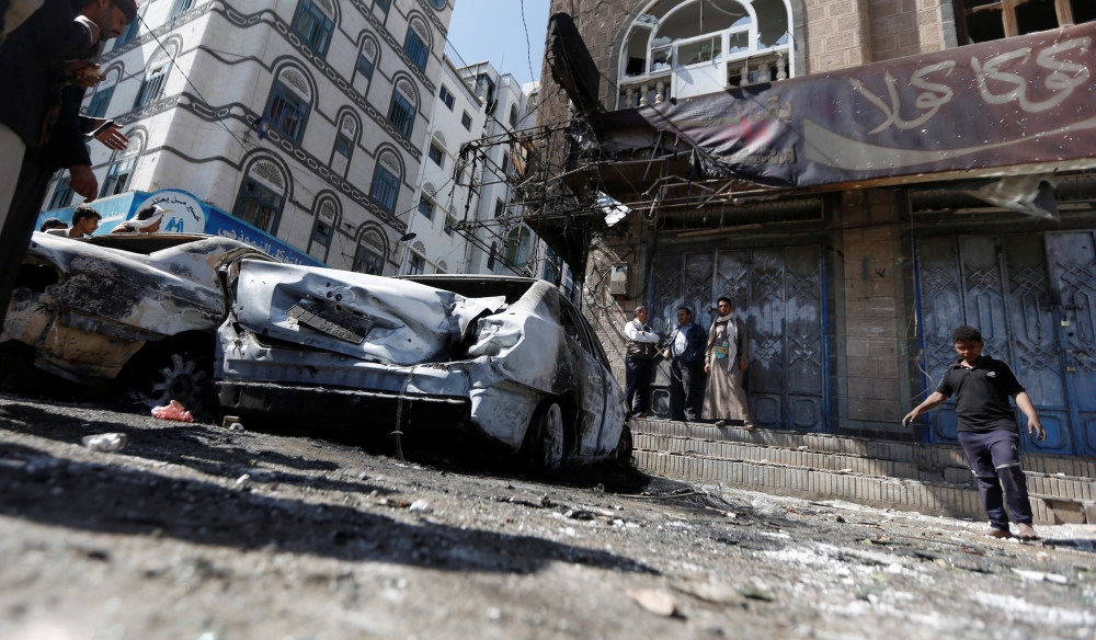 People stand near damaged cars on a street where Houthi fighters recently clashed with forces loyal to Yemen's former president Ali Abdullah Saleh in Sanaa, Yemen December 5, 2017. REUTERS/Khaled Abdullah