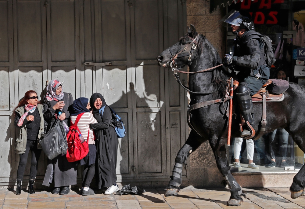 TOPSHOT - Women react as an Israeli mounted policeman disperses Palestinian protesters on December 9, 2017, in East Jerusalem. Retaliatory Israeli air strikes on the Gaza Strip killed two Hamas militants, as unrest simmered across the Palestinian territories over US President Donald Trump's declaration of Jerusalem as Israel's capital. / AFP / Ahmad GHARABLI
