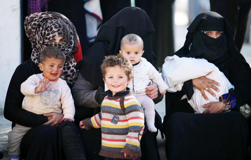 Syrian women and their children wait for food aid in front of an humanitarian aid distrubition center in Syrian border town of Jarablus, Syria, December 13, 2017. REUTERS/Umit Bektas