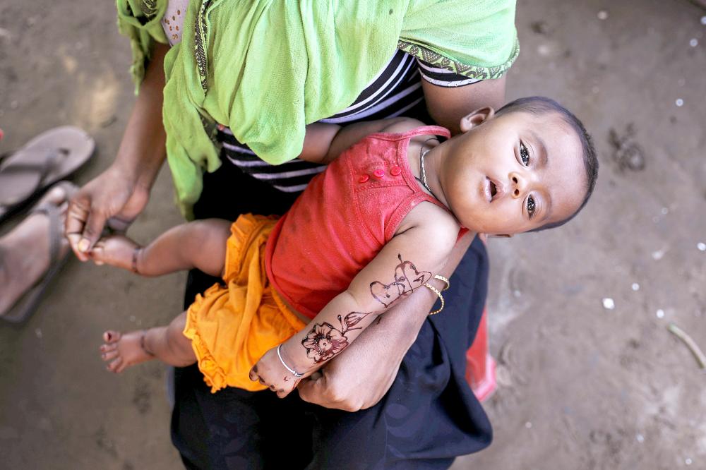 A Rohingya refugee woman holds her child as she sits next to her temporary settlement at the Shamlapur refugee camp near Cox's Bazar, Bangladesh December 20, 2017. REUTERS/Marko Djurica