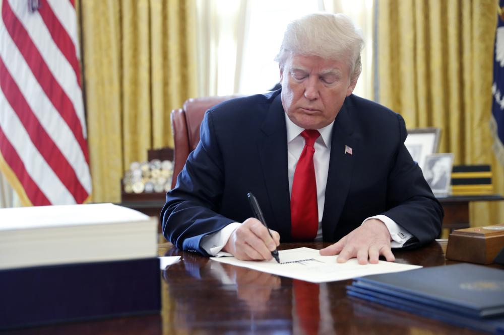 U.S. President Donald Trump signs the $1.5 trillion tax overhaul plan in the Oval Office of the White House in Washington, U.S., December 22, 2017. REUTERS/Jonathan Ernst