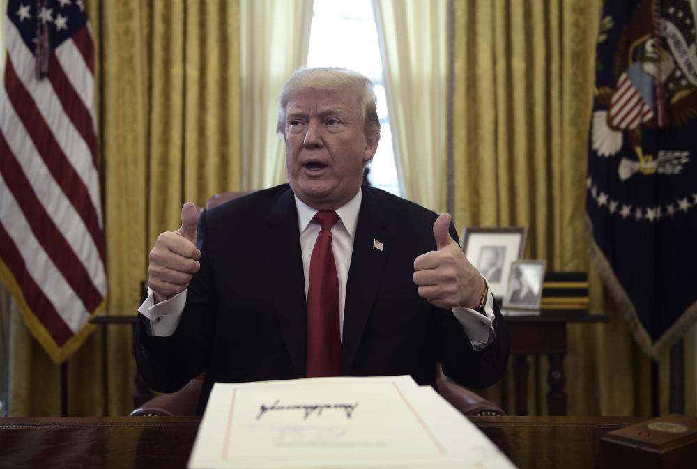 United States President Donald J. Trump talks with the media during an event to sign the Tax Cut and Reform Bill in the Oval Office at The White House in Washington, DC on December 22, 2017.  / AFP / Brendan SMIALOWSKI
