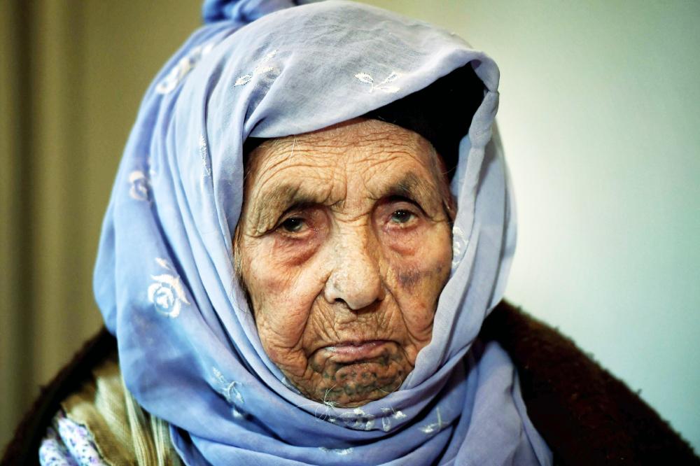 Laila Saleh, a 110 years old Syrian refugee from Kobane, poses for photographes, in Athens on December 15, 2017. Laila Saleh, who was born in Kobane on 1907, also made the dangerous crossing of the Aegean sea with an inflatable boat. She hopes to see again her granddaughter Nasrin, a refugee who found shelter in Germany. Laila Saleh arrived on the Greek island of Lesbos in early November with her grandson Halil, her youngest son Ahmad, Halil's father, her daughter-in-law, and Halil's wife and their two children. / AFP / ARIS MESSINIS
