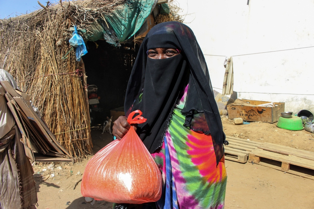 A Yemeni woman carries a bag of lentils distributed as food aid by a local charity at a camp for the displaced, in the northern province of Hajjah on December 23, 2017.  / AFP / STRINGER
