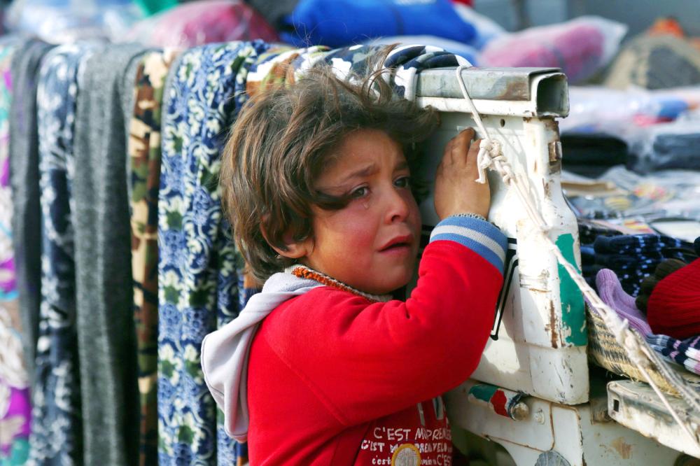 TOPSHOT - A displaced Syrian child, who was forced to leave his hometown by the war against the Islamic State (IS) group, is seen at the Ain Issa camp on December 18, 2017.     As temperatures drop, tens of thousands of civilians forced out of their homes by Syria's war are spending yet another winter in flimsy plastic tents or abandoned half-finished buildings. And without heating, blankets and warm clothes, or access to proper medical care, even a simple cold can turn deadly. / AFP / Delil souleiman
