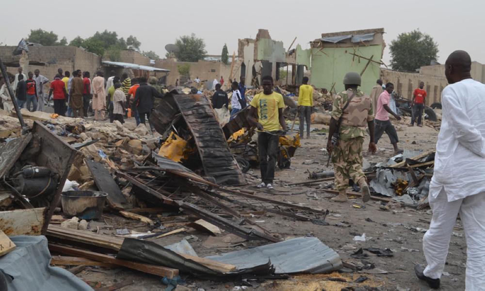 People gather at the site of a twin car bomb explosion in Maiduguri, Nigeria, Sunday, March 2, 2014. Twin car bomb blasts at a bustling marketplace killed at least 51 people in Maiduguri, the northeast Nigerian city that is the birthplace of Nigeria's Islamic extremist terrorist group, a Red Cross official said Sunday. (AP Photo/Jossy Ola )