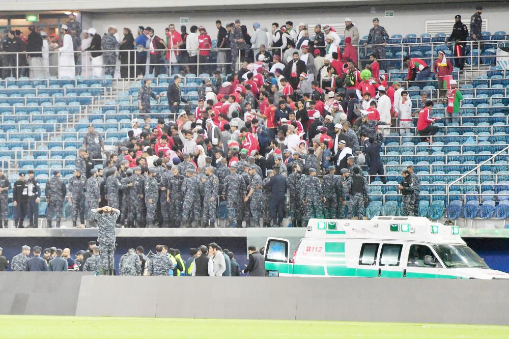 Kuwaiti security guards stand at attention after a glass barrier supporting fans broke at the end of the Gulf Cup of Nations 2017 final football match between Oman and the UAE at the Sheikh Jaber al-Ahmad Stadium in Kuwait City on January 5, 2018.  / AFP / GIUSEPPE CACACE
