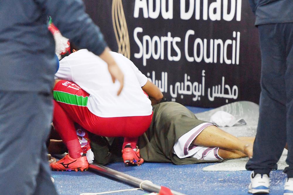 A Omani player checks on a wounded fan after a glass barrier broke at the end of the Gulf Cup of Nations 2017 final football match between Oman and the UAE at the Sheikh Jaber al-Ahmad Stadium in Kuwait City on January 5, 2018.  / AFP / GIUSEPPE CACACE
