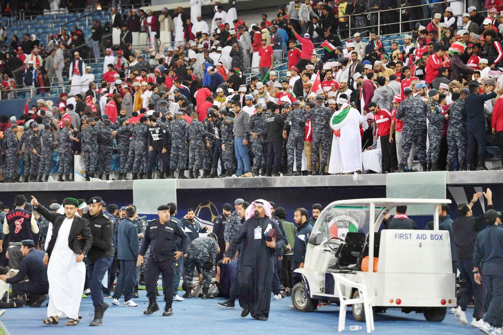 Kuwaiti security guards stand at attention after a glass barrier supporting fans broke at the end of the Gulf Cup of Nations 2017 final football match between Oman and the UAE at the Sheikh Jaber al-Ahmad Stadium in Kuwait City on January 5, 2018.  / AFP / GIUSEPPE CACACE
