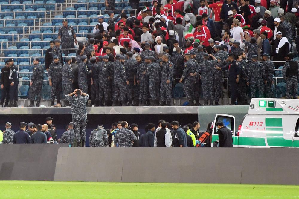 Kuwaiti security guards stand at attention after a glass barrier supporting fans broke at the end of the Gulf Cup of Nations 2017 final football match between Oman and the UAE at the Sheikh Jaber al-Ahmad Stadium in Kuwait City on January 5, 2018.  / AFP / GIUSEPPE CACACE
