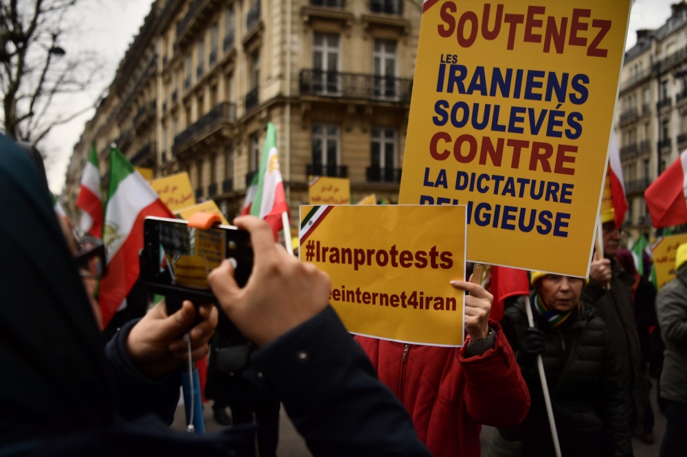 Protesters hold placards reading 