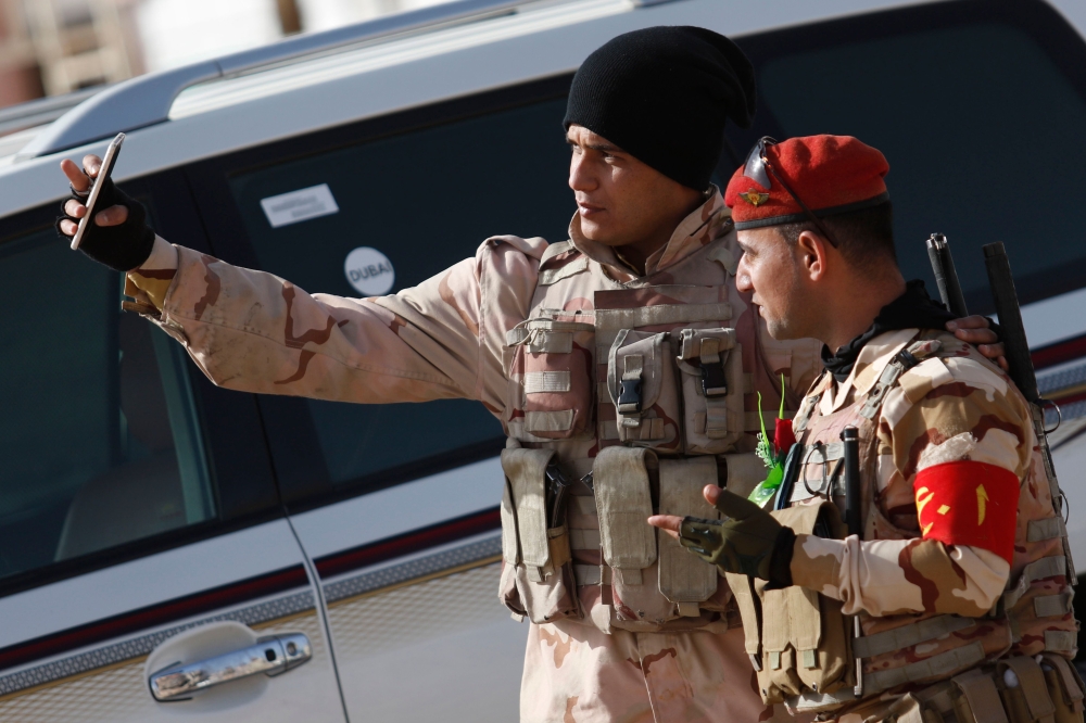 Iraqi soldiers take a selfie during a ceremony marking Iraq's 97th Army Day on January 6, 2018, in the southern city of Basra.  / AFP / HAIDAR MOHAMMED ALI
