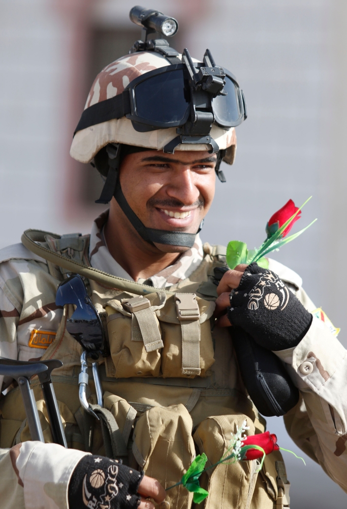 An Iraqi soldier receives roses from children during a ceremony marking Iraq's 97th Army Day on January 6, 2018, in the southern city of Basra.  / AFP / HAIDAR MOHAMMED ALI
