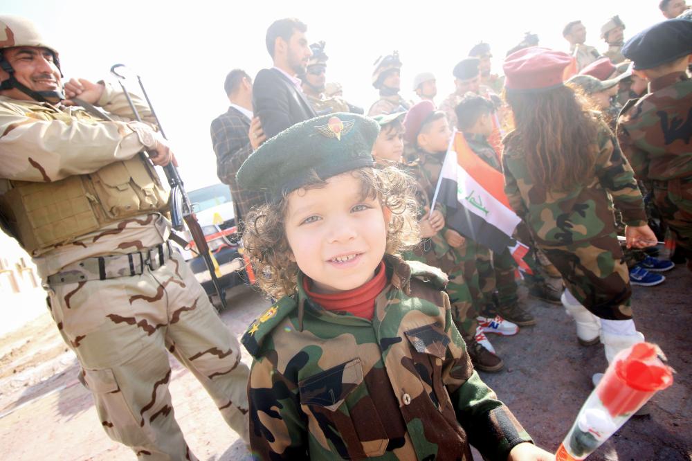 Iraqi children wearing military fatigues attend a ceremony with soldiers during festivities marking Iraq's 97th Army Day on January 6, 2018, in the southern city of Basra.  / AFP / HAIDAR MOHAMMED ALI
