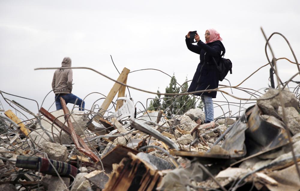 



فلسطينية توثق بهاتفها الدمار الذي أحدثه الاحتلال عقب هدم منزل فلسطيني في الضفة أمس. (أ ف ب)
