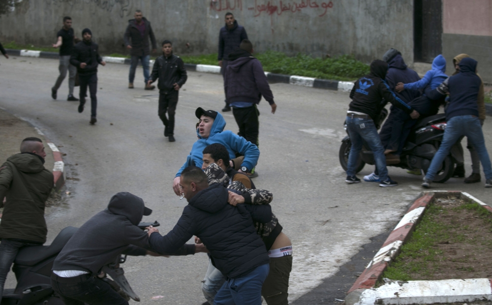 Palestinian youths evacuate a wounded comrade during clashes with Israeli forces in Jenin, in the north of the occupied West Bank, on January 18, 2018.  A Palestinian was killed during clashes with Israeli forces in Jenin, the Palestinian health ministry announced. Israel's Shin Beth security services said shots were fired during a raid by border guards to capture the alleged perpetrators of an attack earlier this month in which a rabbi was shot dead.
 / AFP / JAAFAR ASHTIYEH
