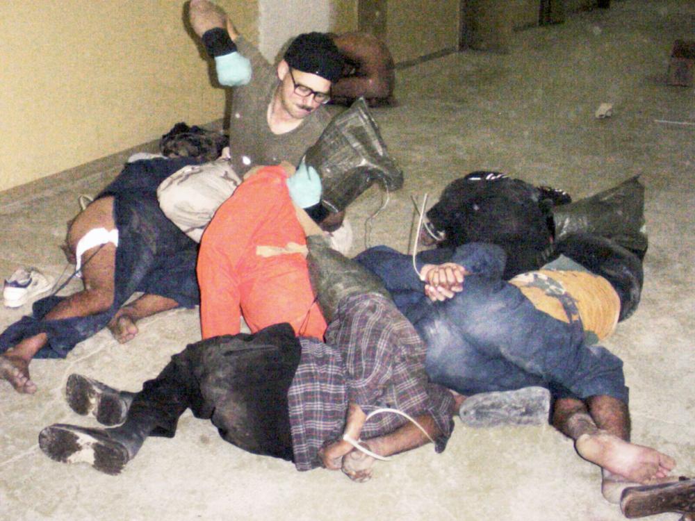 *MANDATORY CREDIT TO THE WASHINGTON POST* In this undated still photo, received 21 May 2004, an unidentified US soldier appears poised to punch a Iraqi detainee at Abu Ghraib Prison,out side of Baghdad, as other detainees lay bound at the hands and hooded. Detainee at right appears to be partially clothed. AFP PHOTO/ **MANDATORY CREDIT TO THE WASHINGTON POST**INTERNET OUT**NO SALES**