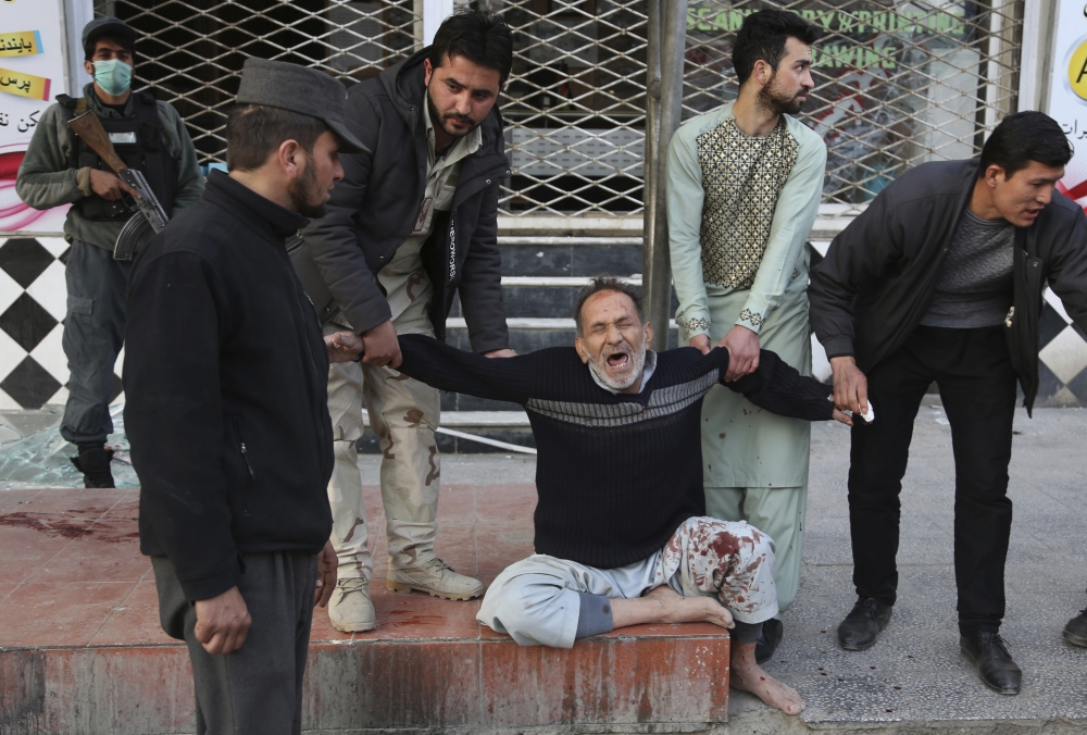 A relative of a victim is helped as he cries after a deadly suicide attack in Kabul, Afghanistan, Saturday Jan. 27, 2018. Authorities say suicide car bomber killed dozens of people and wounded over 100 in an attack claimed by the Taliban in the Afghan capital Kabul, authorities said. (AP Photo/Rahmat Gul)