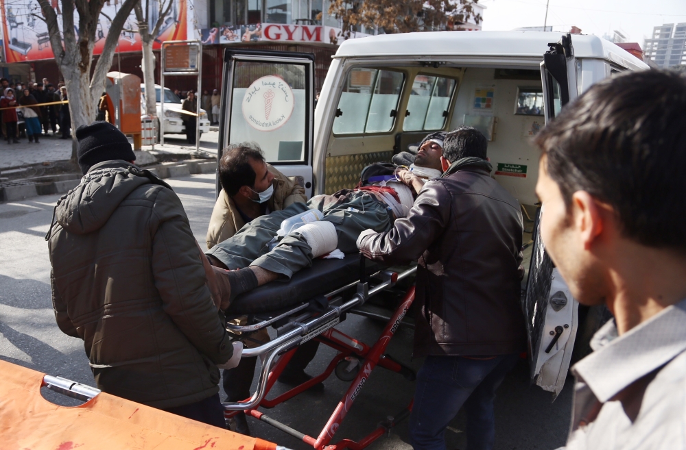 People help carry an injured man to the hospital following a suicide attack in Kabul, Afghanistan, Saturday Jan. 27, 2018. The Public Health Ministry says dozens were killed and over 100 wounded in a suicide car bombing in downtown Kabul. (AP Photo/ Rahmat Gul)