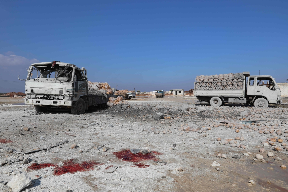 A picture taken on January 29, 2018 shows blood stains on the ground next to trucks loaded with sacks of potatoes standing abandoned after their windows were blasted from their frames following airstrikes by government forces which hit the vegetable market of the town of Saraqeb in Syria's northwestern province of Idlib. Syrian troops had been advancing on Idlib as part of a fierce offensive launched in late December with Russian backing. / AFP / OMAR HAJ KADOUR
