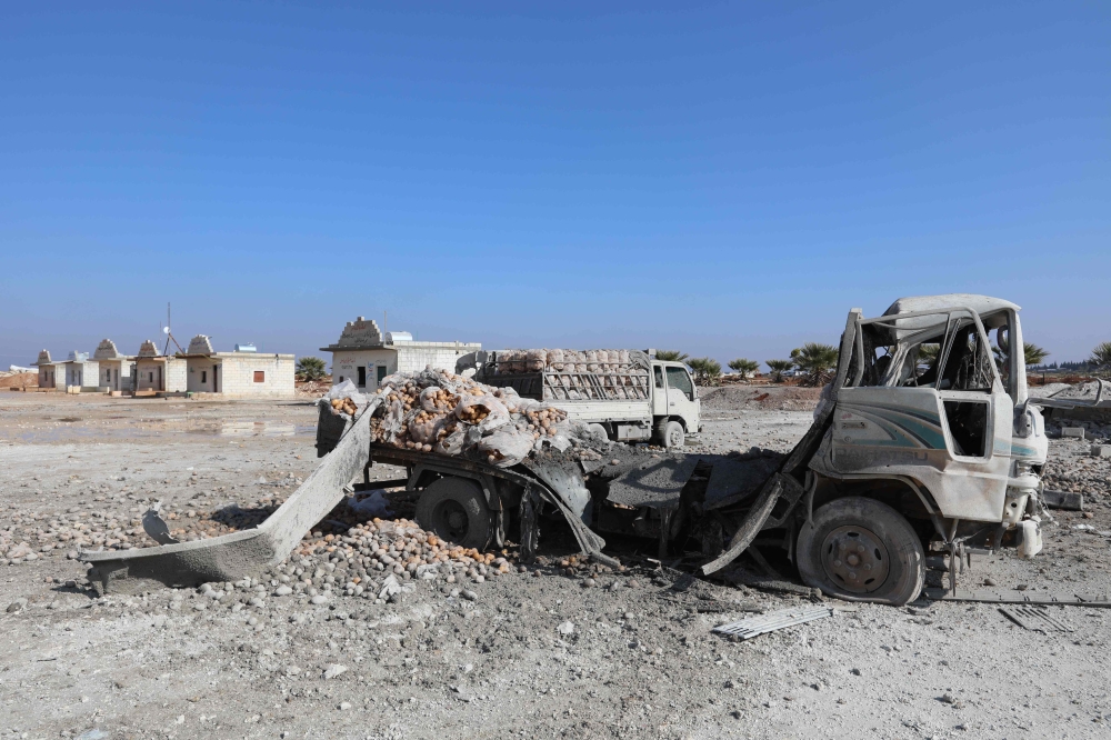 A picture taken on January 29, 2018 shows trucks loaded with sacks of potatoes standing abandoned after their windows were blasted from their frames following airstrikes by government forces which hit the vegetable market of the town of Saraqeb in Syria's northwestern province of Idlib. Syrian troops had been advancing on Idlib as part of a fierce offensive launched in late December with Russian backing. / AFP / OMAR HAJ KADOUR
