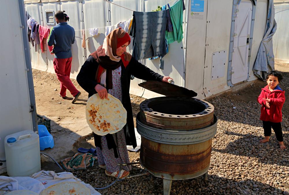 Umm Abdullah bakes bread in the street of a camp for internally displaced people in western Baghdad, Iraq, Thursday, Feb. 1, 2018. (AP Photo/Karim Kadim)