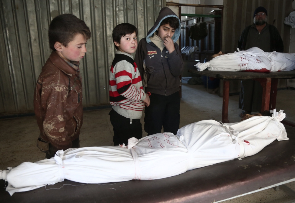 TOPSHOT - Children stand over the body of a child at a makeshift hospital, following an airstrike in the rebel-held besieged town of Arbin, in the eastern Ghouta region on the outskirts of the capital Damascus on February 2, 2018. / AFP / ABDULMONAM EASSA
