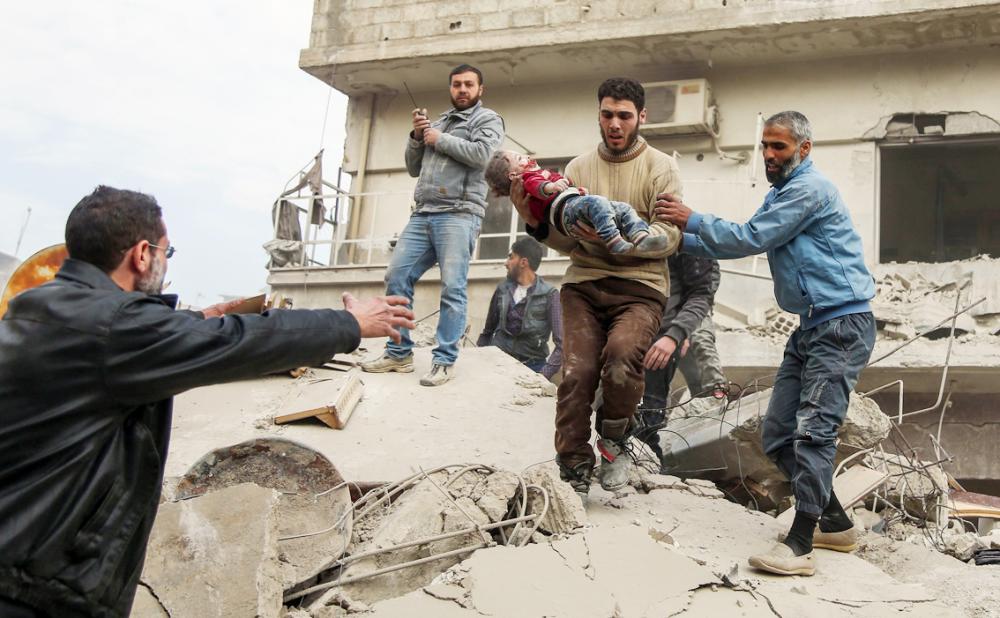 EDITORS NOTE: Graphic content / Syrian men carry a rescued child from beneath the ruins of a building that collapsed following reported Syrian air force strikes in the rebel-held town of Saqba, in the besieged Eastern Ghouta region on the outskirts of the capital Damascus, on February 6, 2018. Fresh regime strikes on a besieged rebel-held enclave near Damascus killed more than 60 civilians on February 6, despite mounting Western pressure on Syrian President Bashar al-Assad. / AFP / ABDULMONAM EASSA
